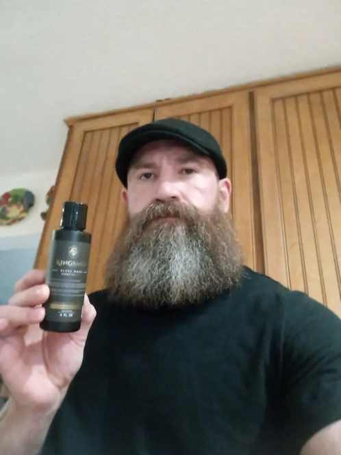 Person with a beard holding a bottle of beard oil.