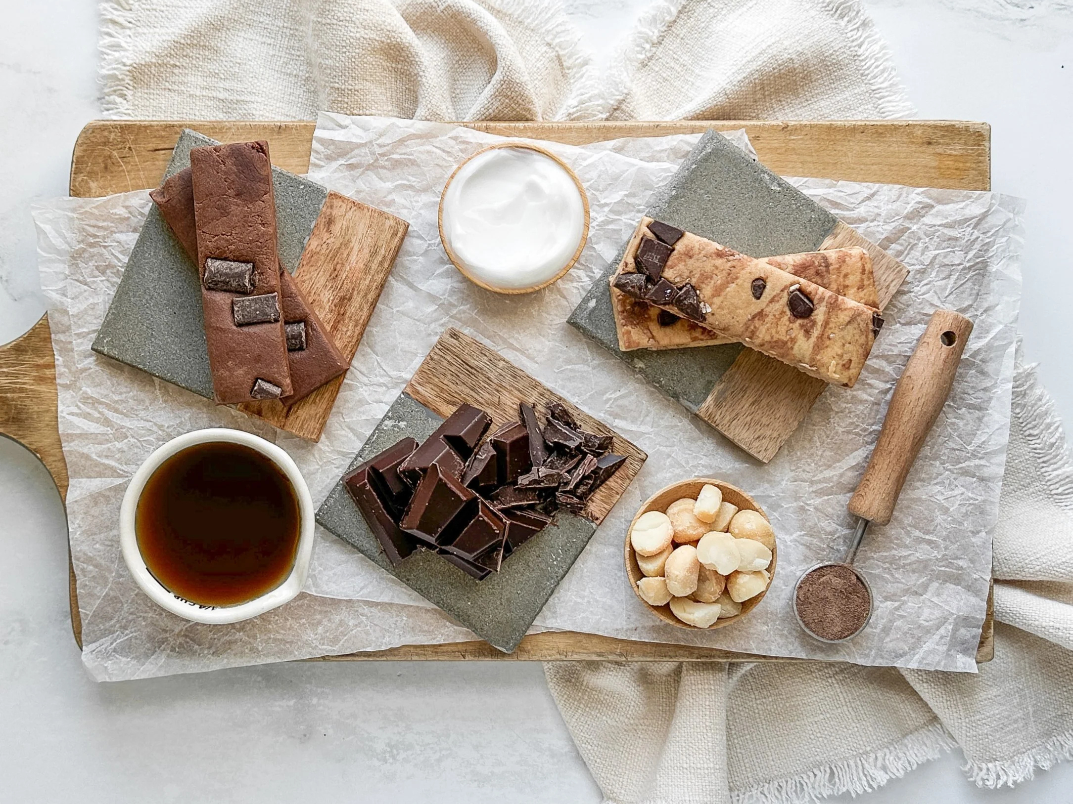 Assorted chocolate bars, nuts, and a cup of tea on a wooden board.