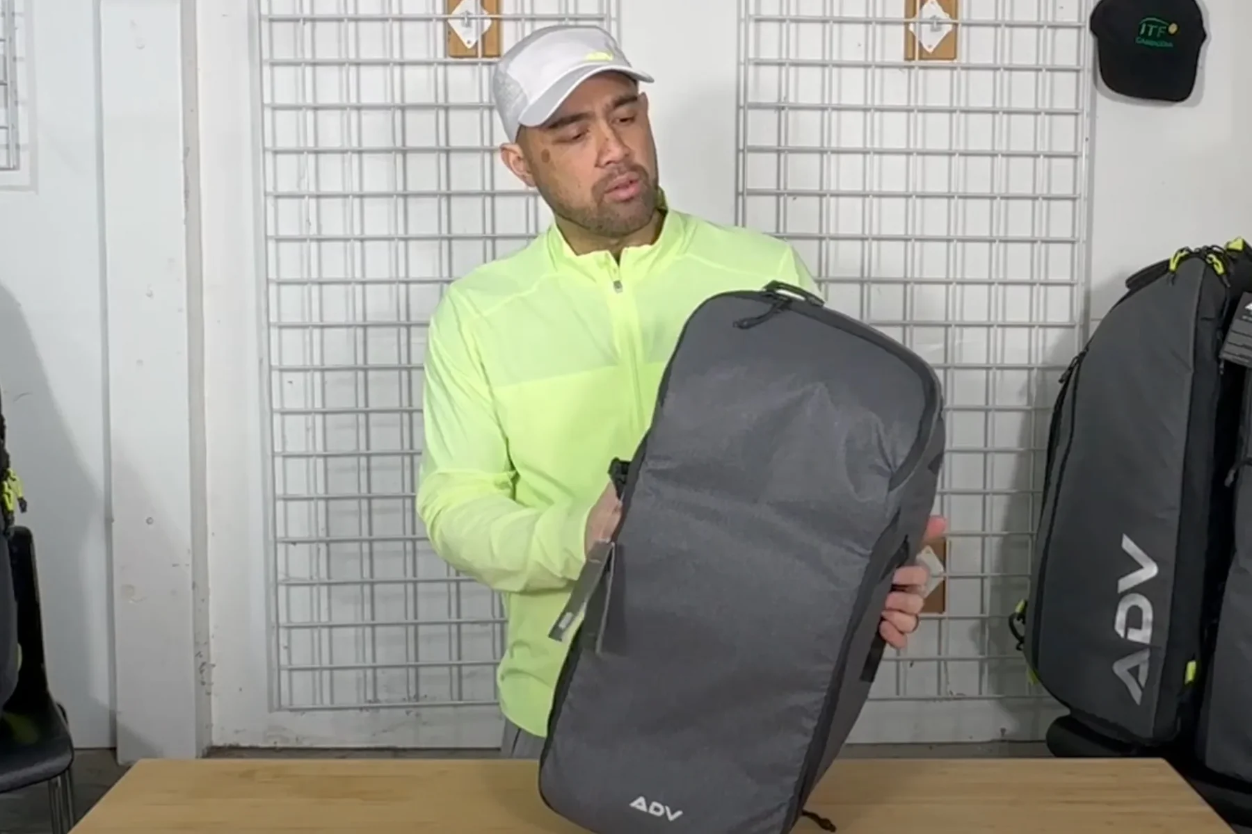 Person in a yellow jacket holding a gray backpack indoors.