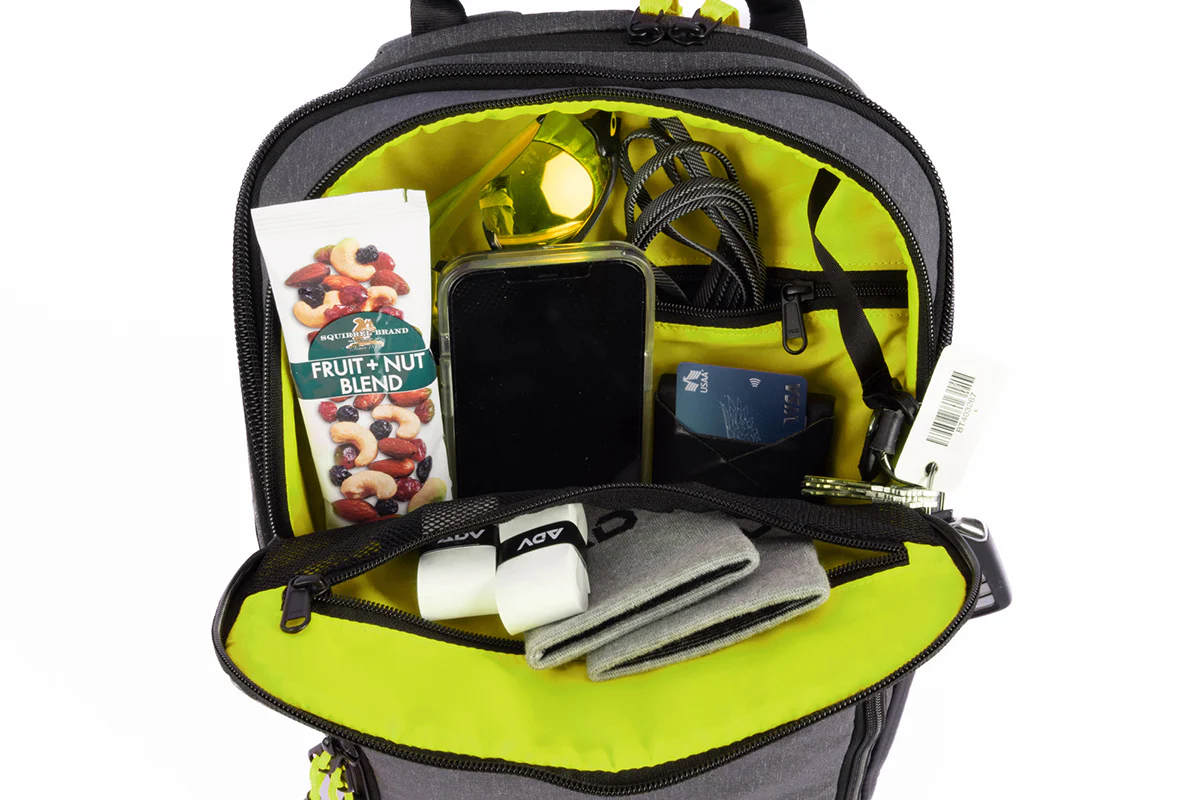 Open backpack with snacks, phone, cables, and cards inside.