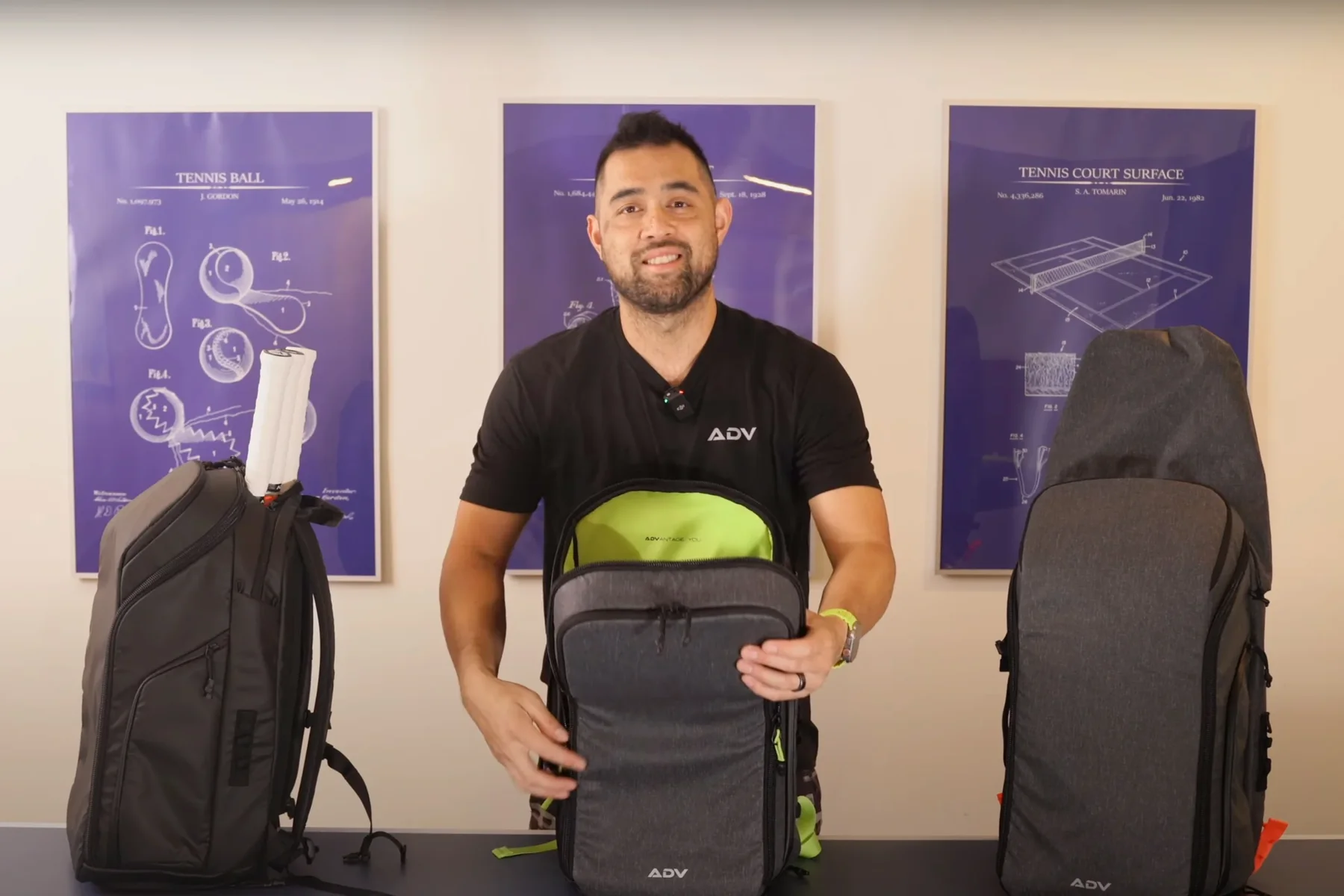 Person displaying tennis bags with blueprint posters in the background.