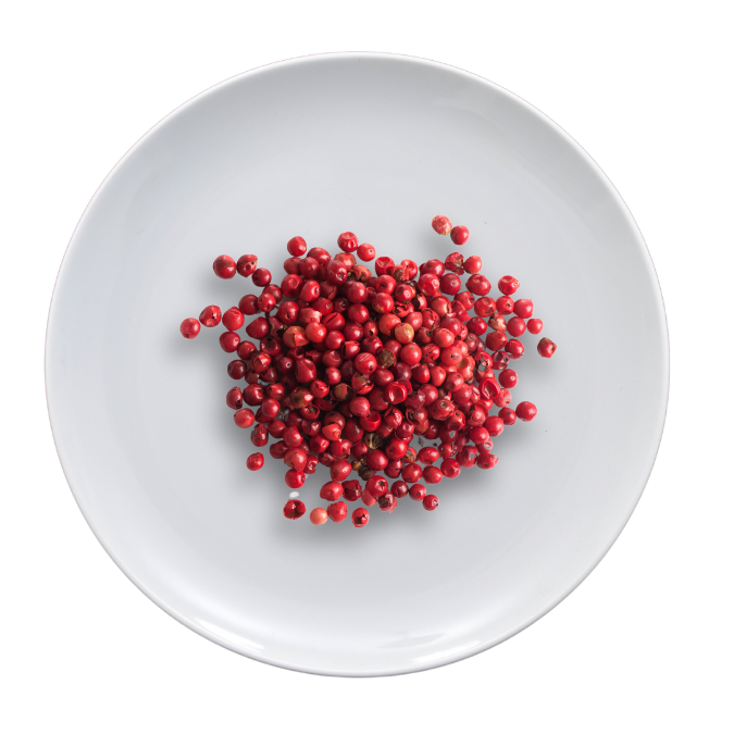 A pile of red peppercorns on a white plate.