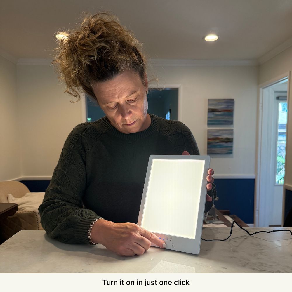 Person holding and turning on a large light panel on a table.