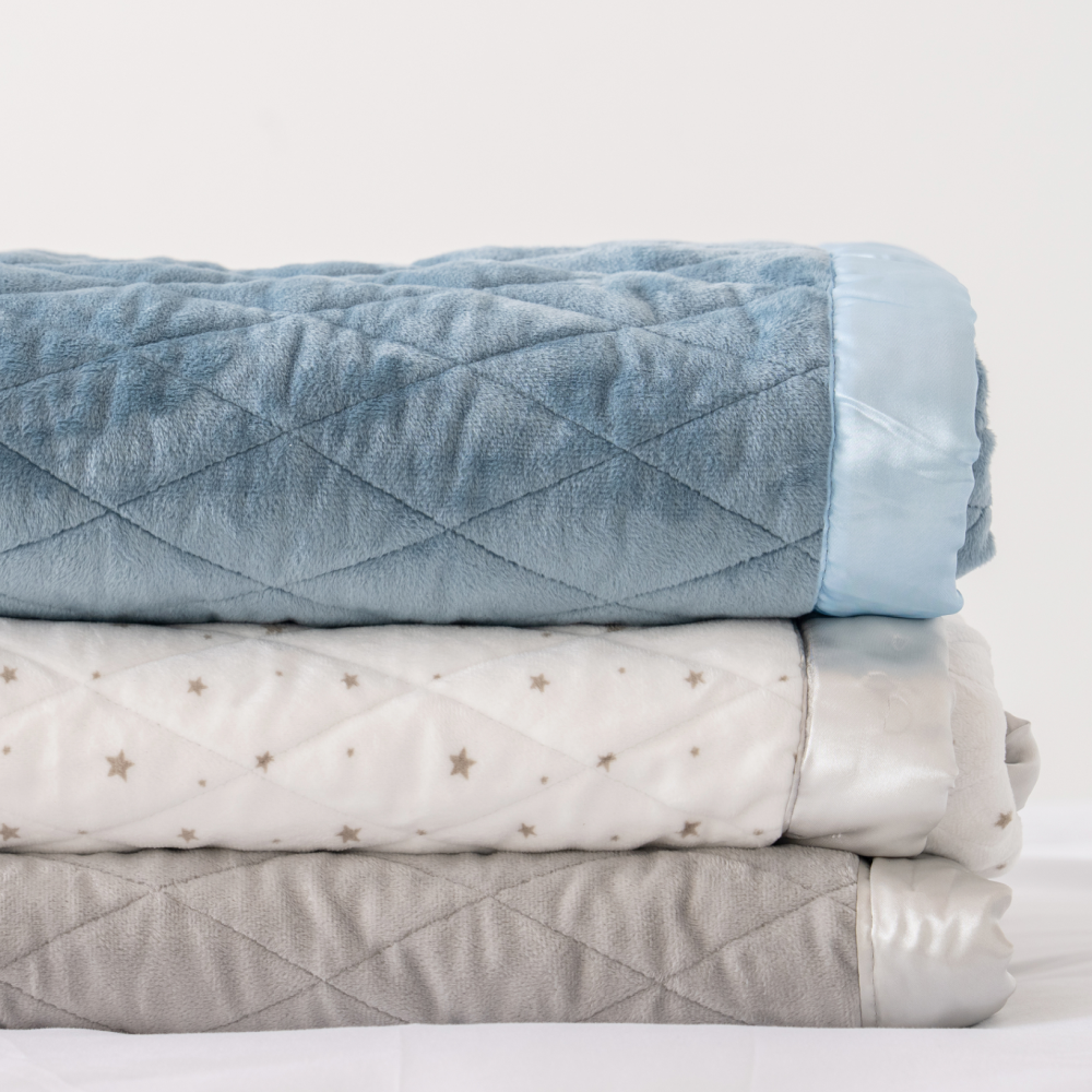 Stack of three folded blankets in blue, white with stars, and gray.