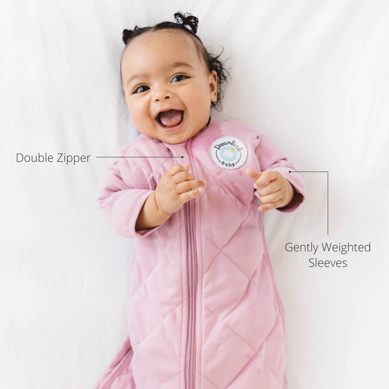 Smiling baby in pink sleep sack with double zipper and gently weighted sleeves.