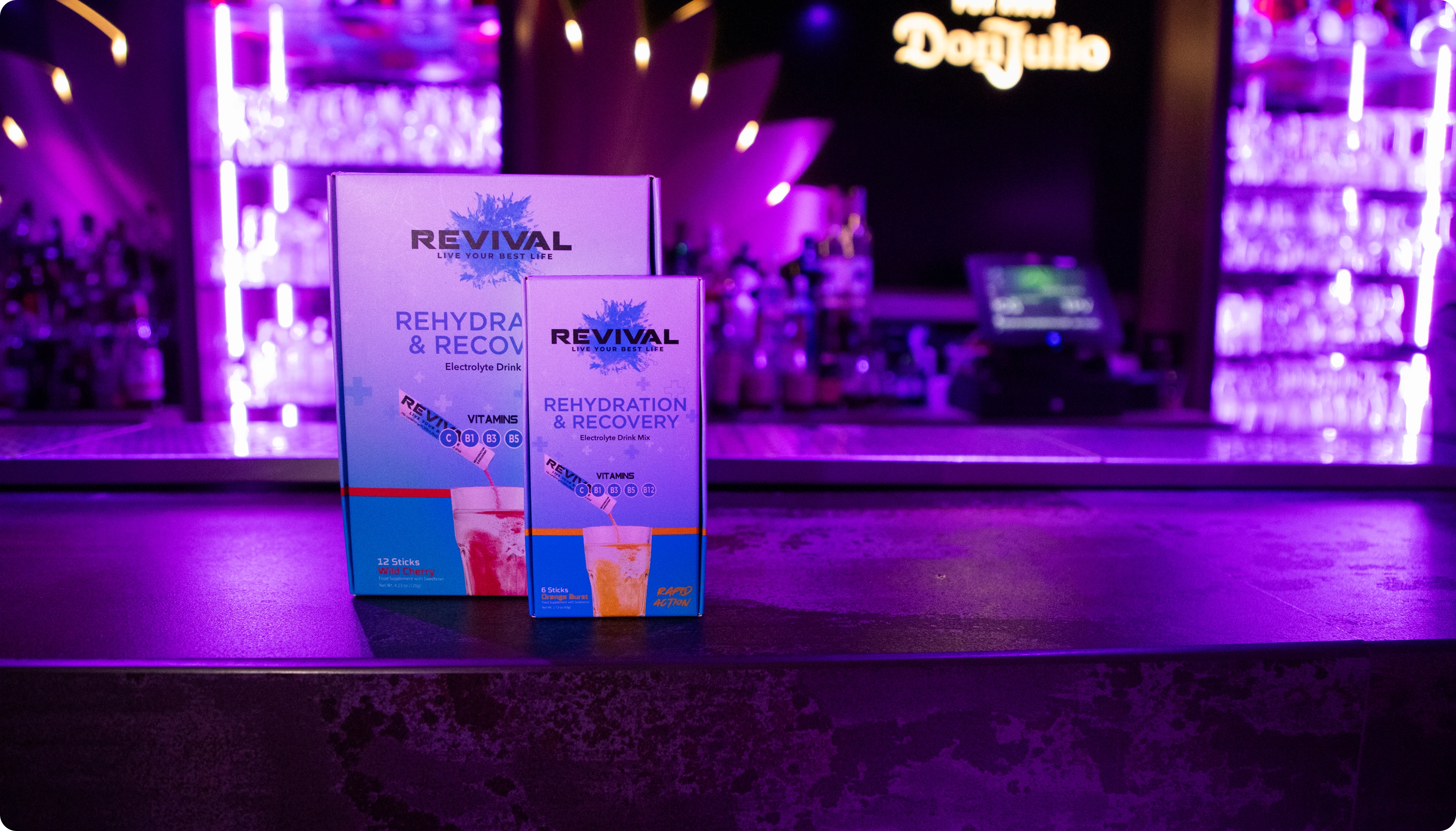 A box of Revival Rehydration & Recovery drink mix on a table next to a frozen cocktail.