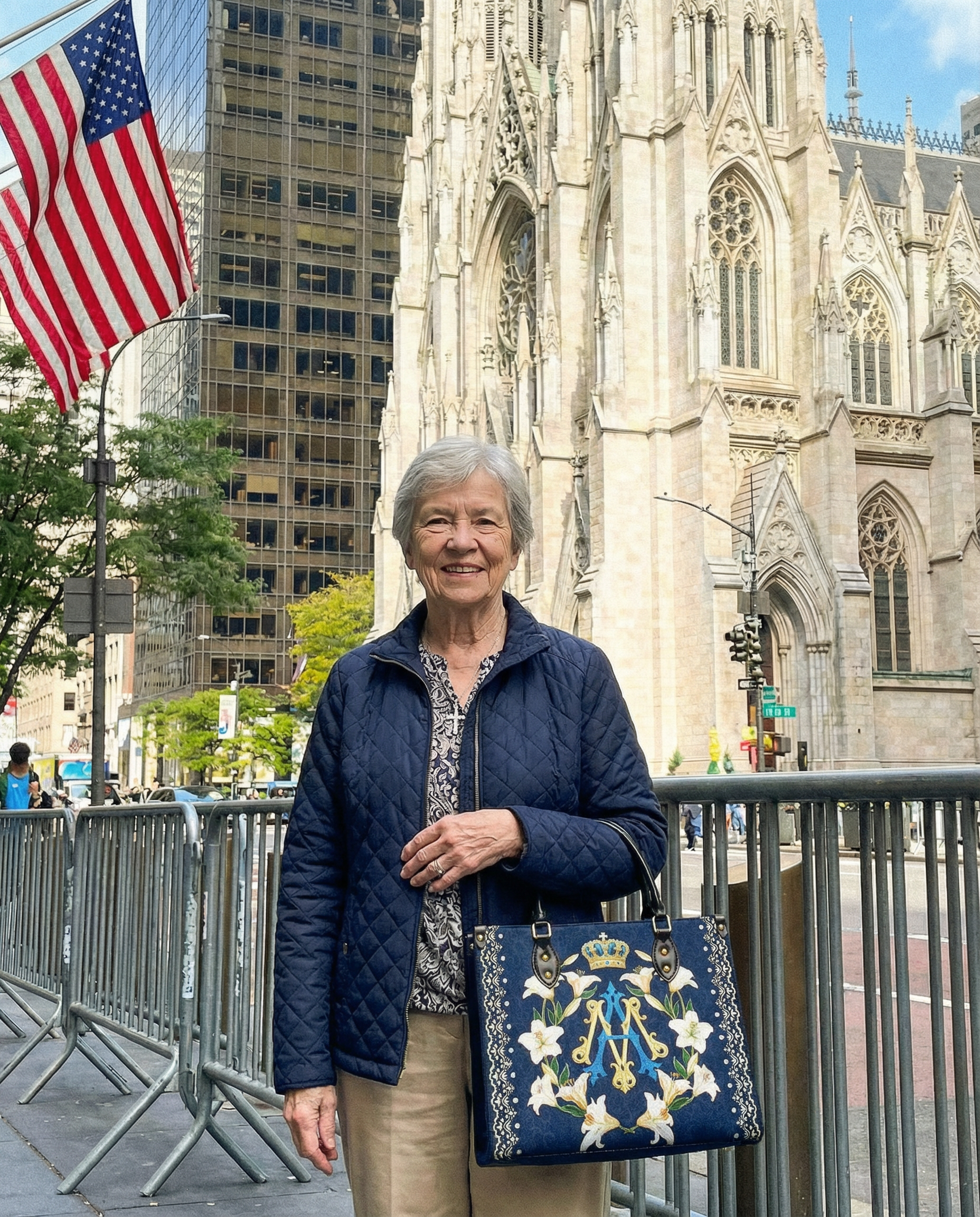 A woman smiles on a city street in front of a large cathedral, a skyscraper, and an American flag.
