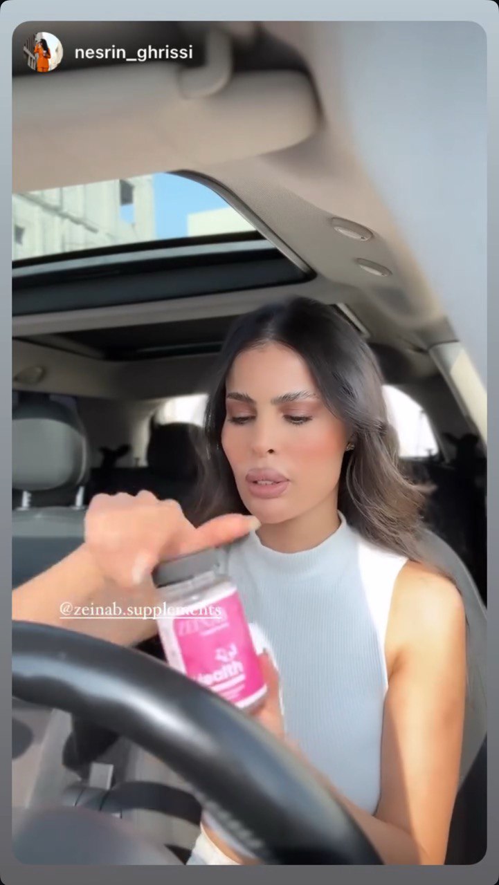A person in a car holding a bottle of supplements.