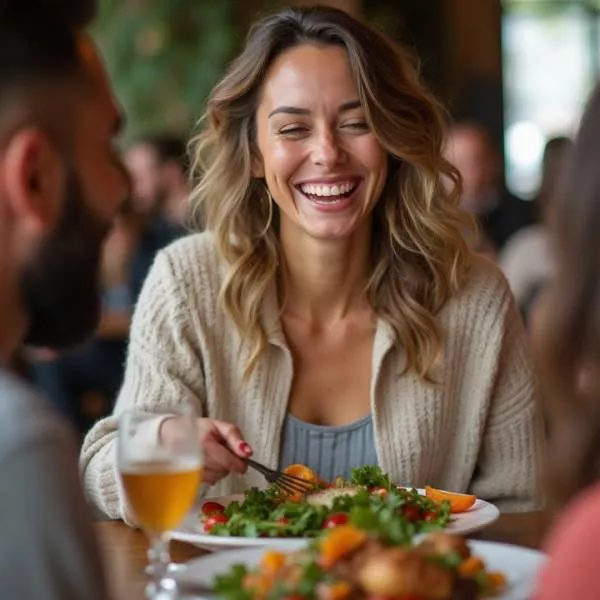 Smiling woman enjoying a meal with friends at a restaurant.