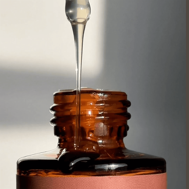 Close-up of Glow  liquid dripping into a brown glass bottle.
