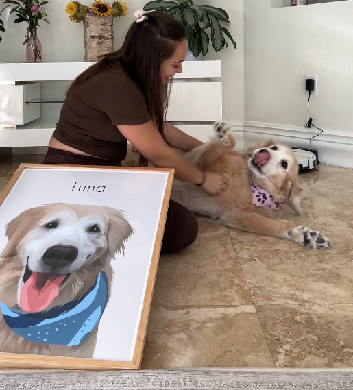 Woman playing with a dog next to a framed dog portrait.