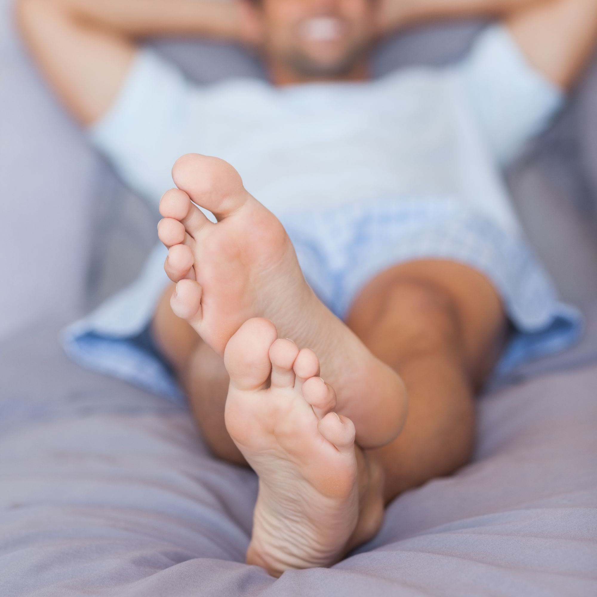 Person lying on a bed with feet in focus.