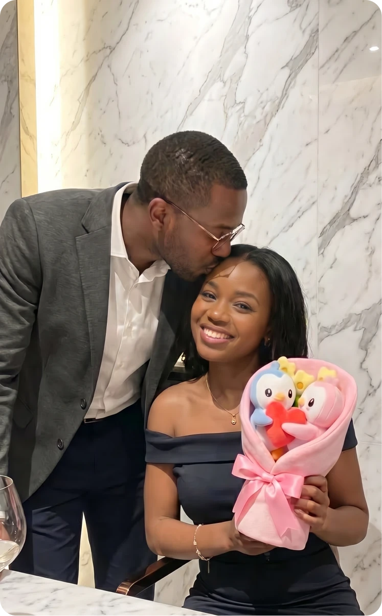 A man kisses a smiling woman on the forehead as she holds a bouquet of plush toys.