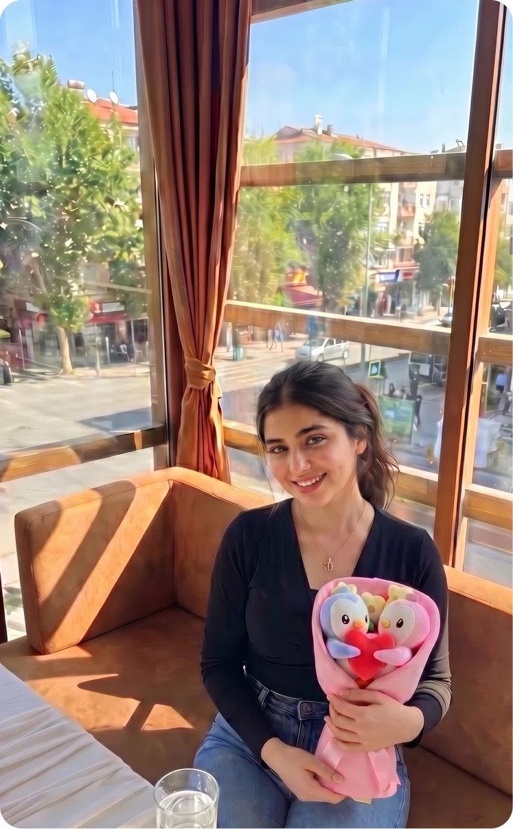 A young woman sits in a restaurant booth by a sunny window, holding a bouquet of plush toys.