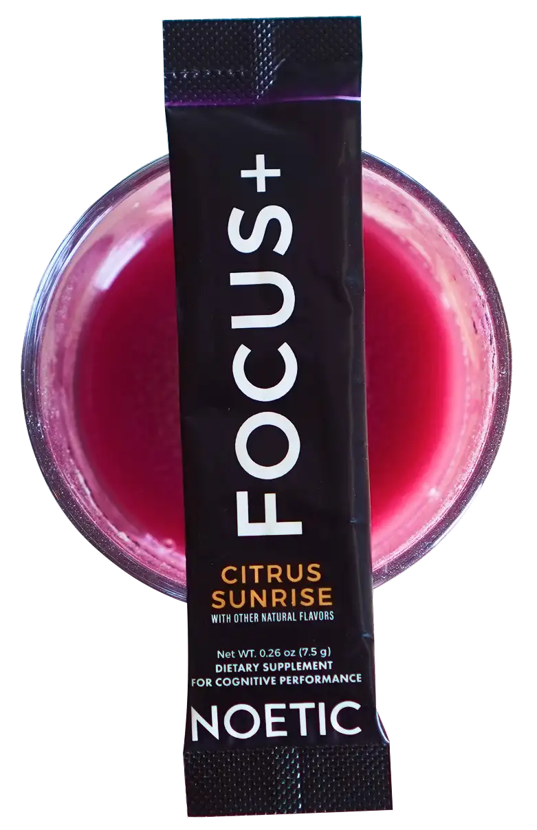 Black packet labeled 'FOCUS+' on a glass of pink liquid.