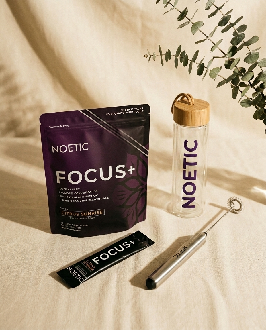 A pouch of Noetic Focus+ supplement, a branded glass bottle, a stick pack, and a frother.