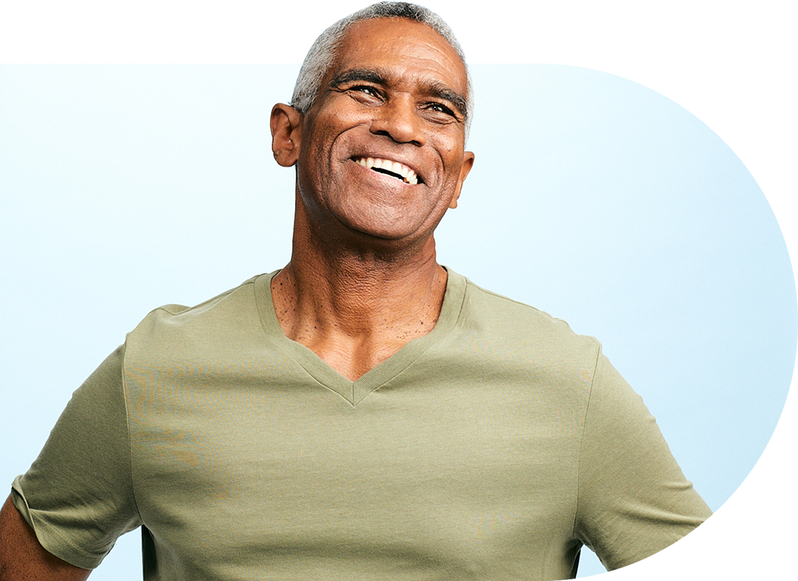Smiling man in a green shirt against a light blue background.