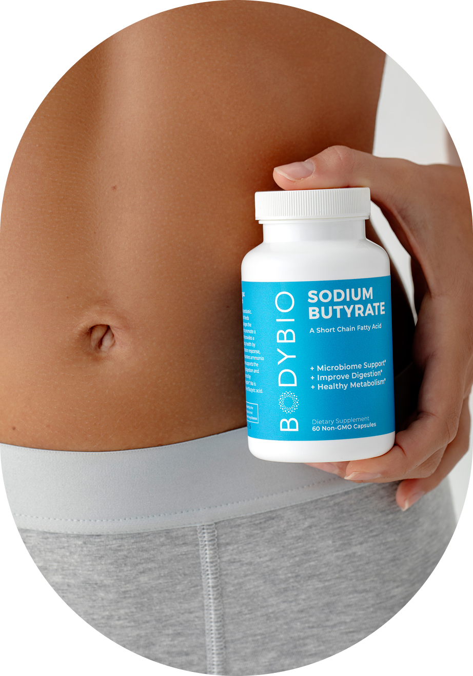 Person holding a bottle of sodium butyrate near their waist.