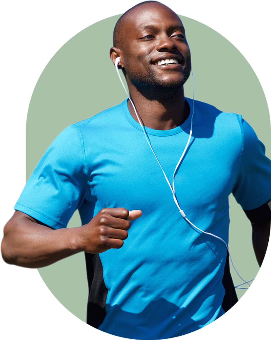 Man jogging with earphones, wearing a blue shirt, smiling.