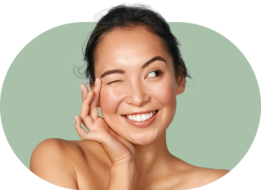 Smiling person winking with hand on face against a green background.