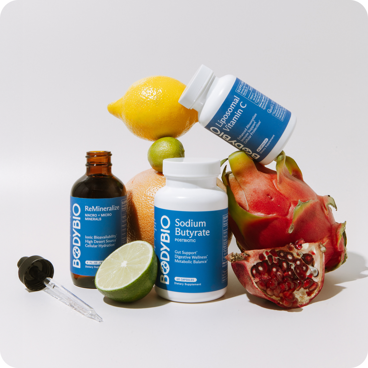 Assorted dietary supplements surrounded by various fruits on a white background.