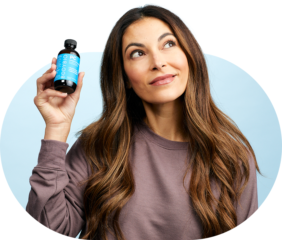 Woman holding a bottle, pondering thoughtfully, against a light blue background.