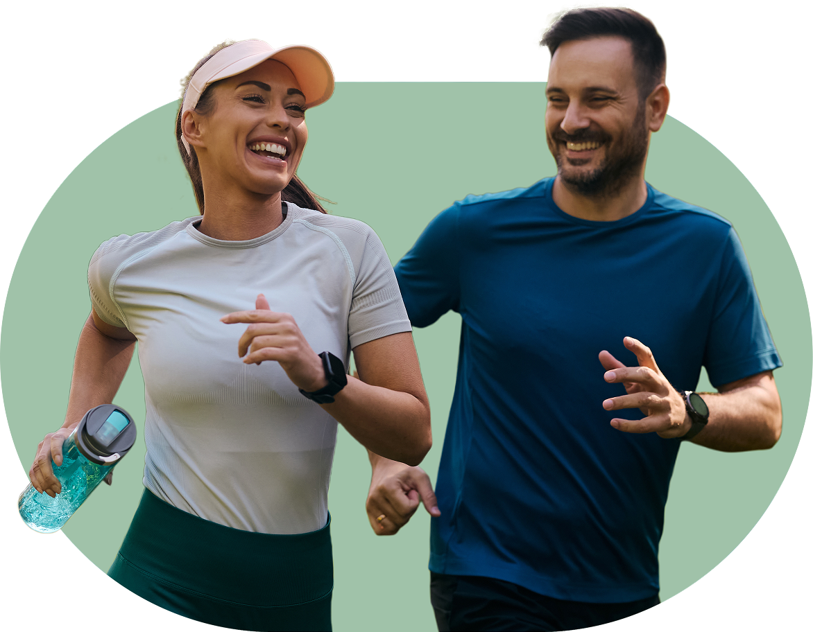 Two people jogging and smiling, holding drinks, against a plain background.