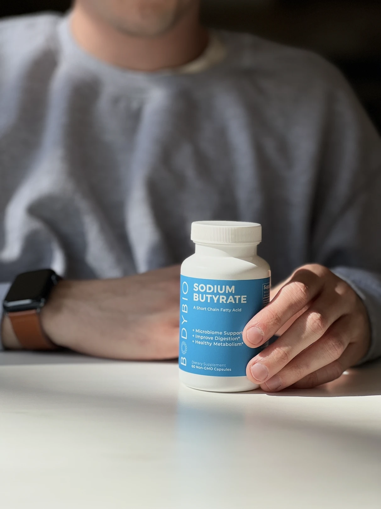 Person holding a bottle of sodium butyrate supplement.