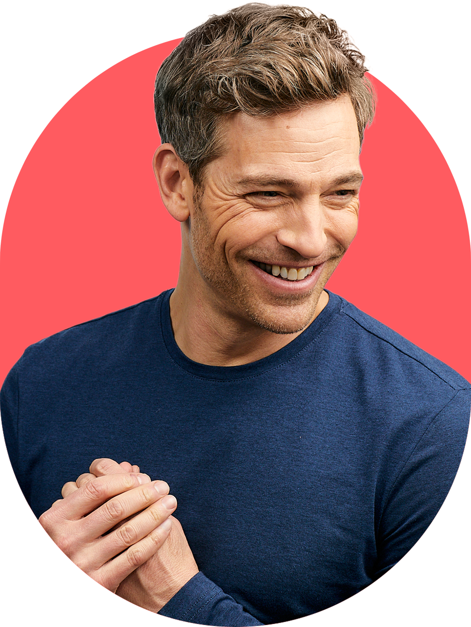 Smiling man in a blue shirt against a red background.