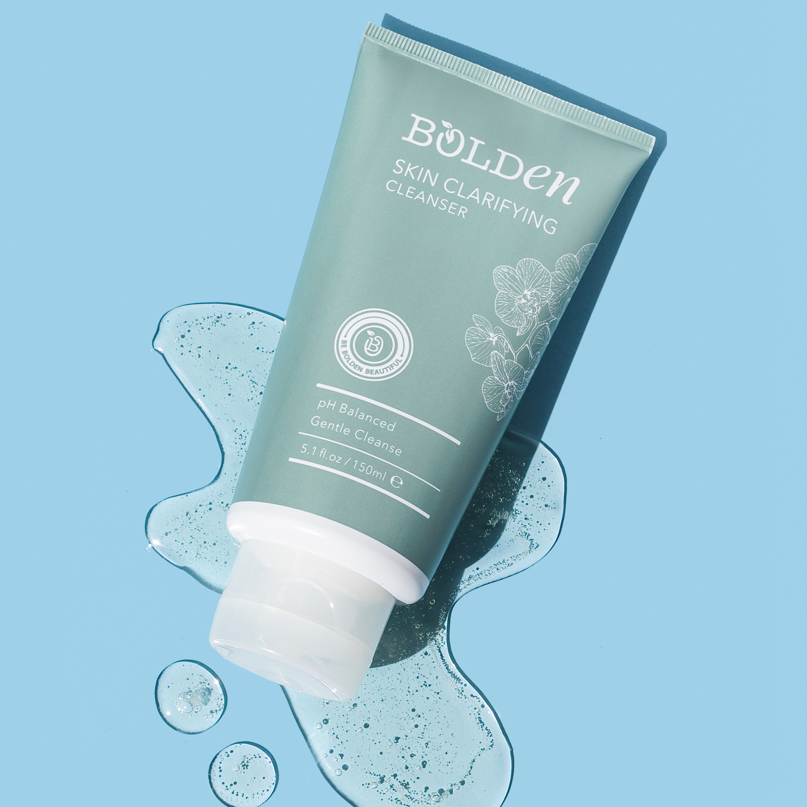A tube of Bolden Skin Clarifying Cleanser lies in a smear of clear gel on a blue background.