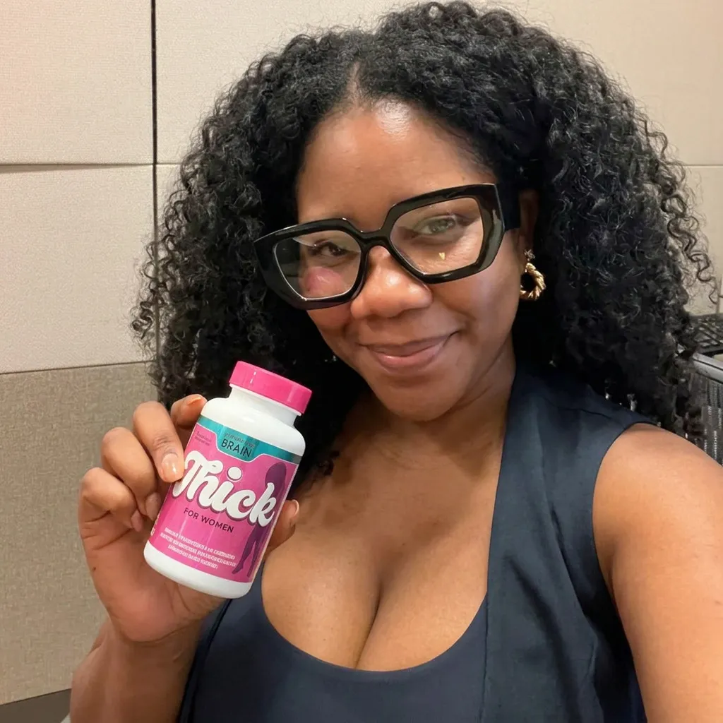 A woman with glasses smiles while holding up a pink and white bottle of 'Thick for Women' supplements.