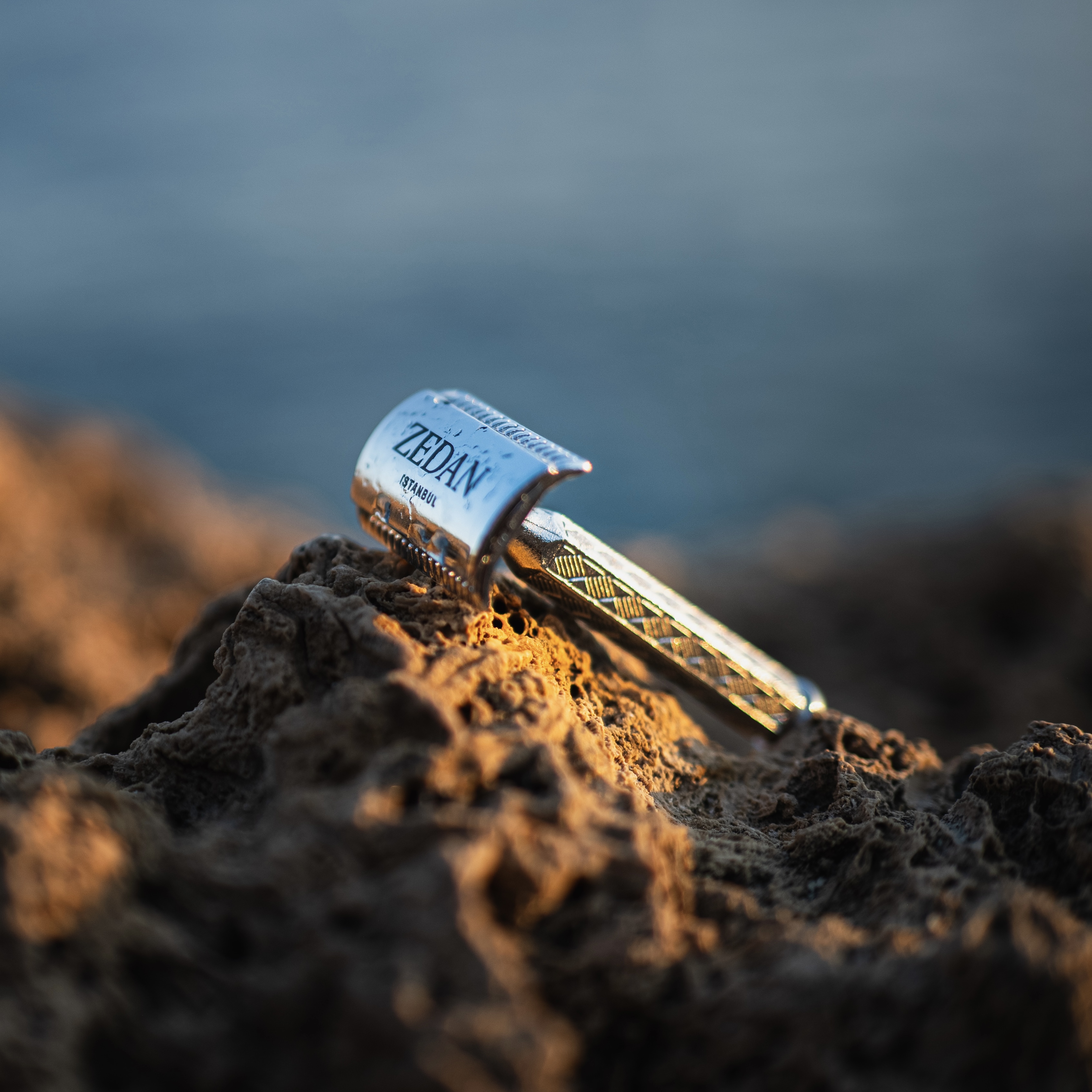 A metal razor resting on a rocky surface.