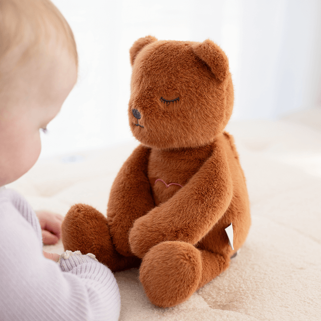 Person knitting a yellow and grey blanket on a black couch.
