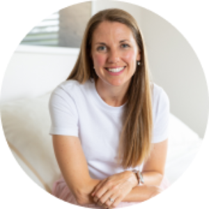 Person knitting a yellow and grey blanket on a black couch.