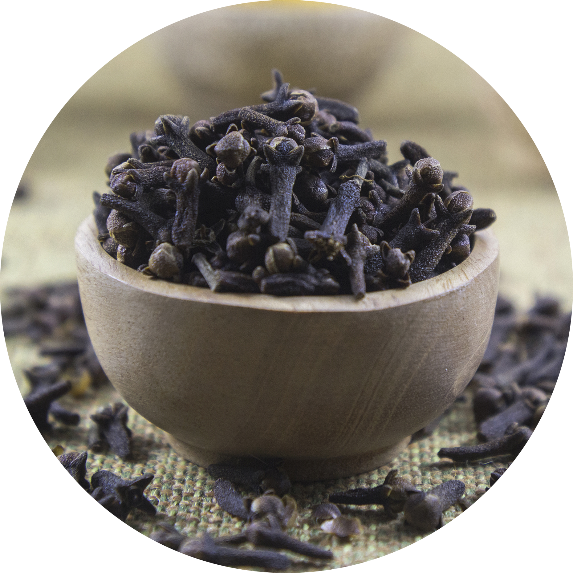 A wooden bowl filled with dried cloves on a textured surface.