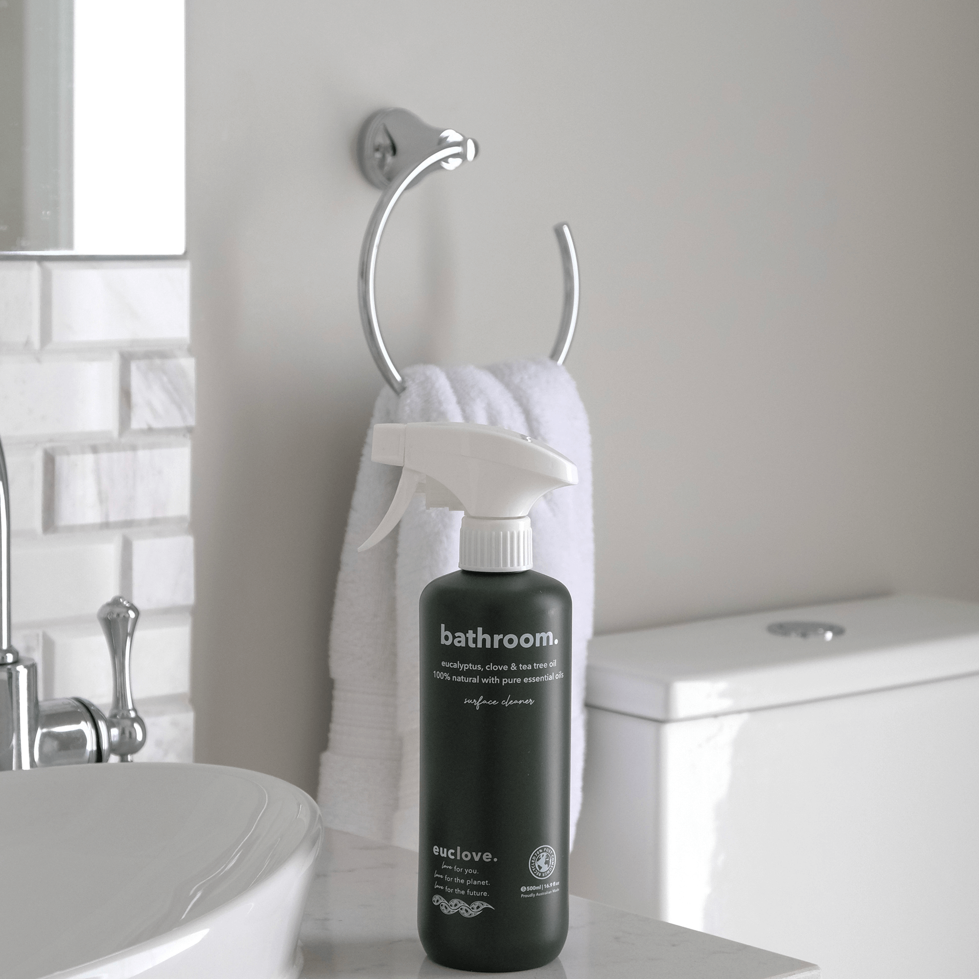 Bathroom cleaner bottle on a counter near a towel and sink.