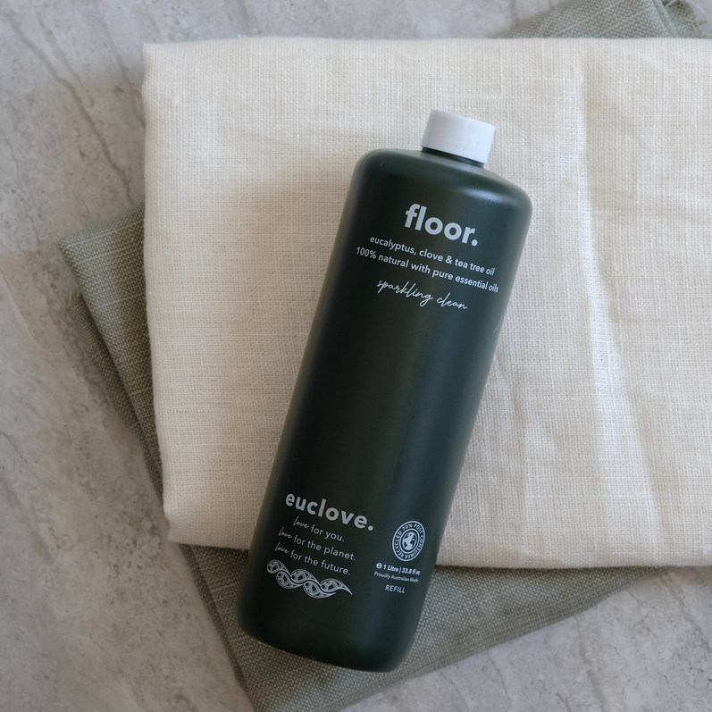 Dark green bottle of floor cleaner on folded cloths.