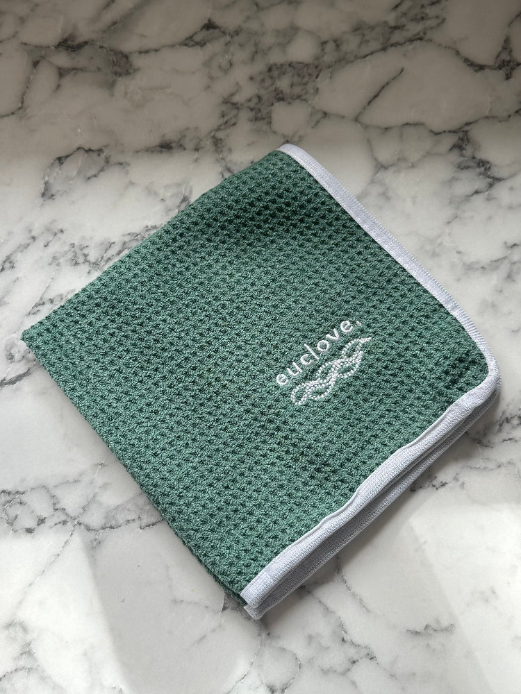 A folded, gray microfiber cleaning cloth with the brand name 'euclove' on a marble surface.
