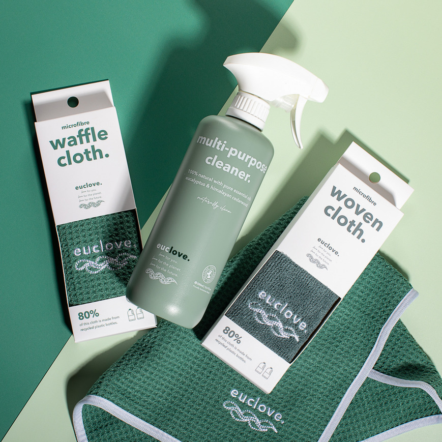 Green cleaning products and cloths on a green background.