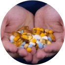 Hands holding a variety of colorful pills and capsules.