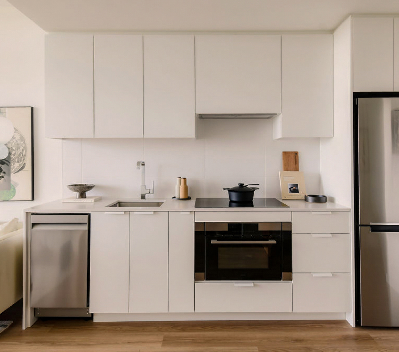Minimal kitchen interior with white cabinets, built-in oven, and stainless steel appliances.