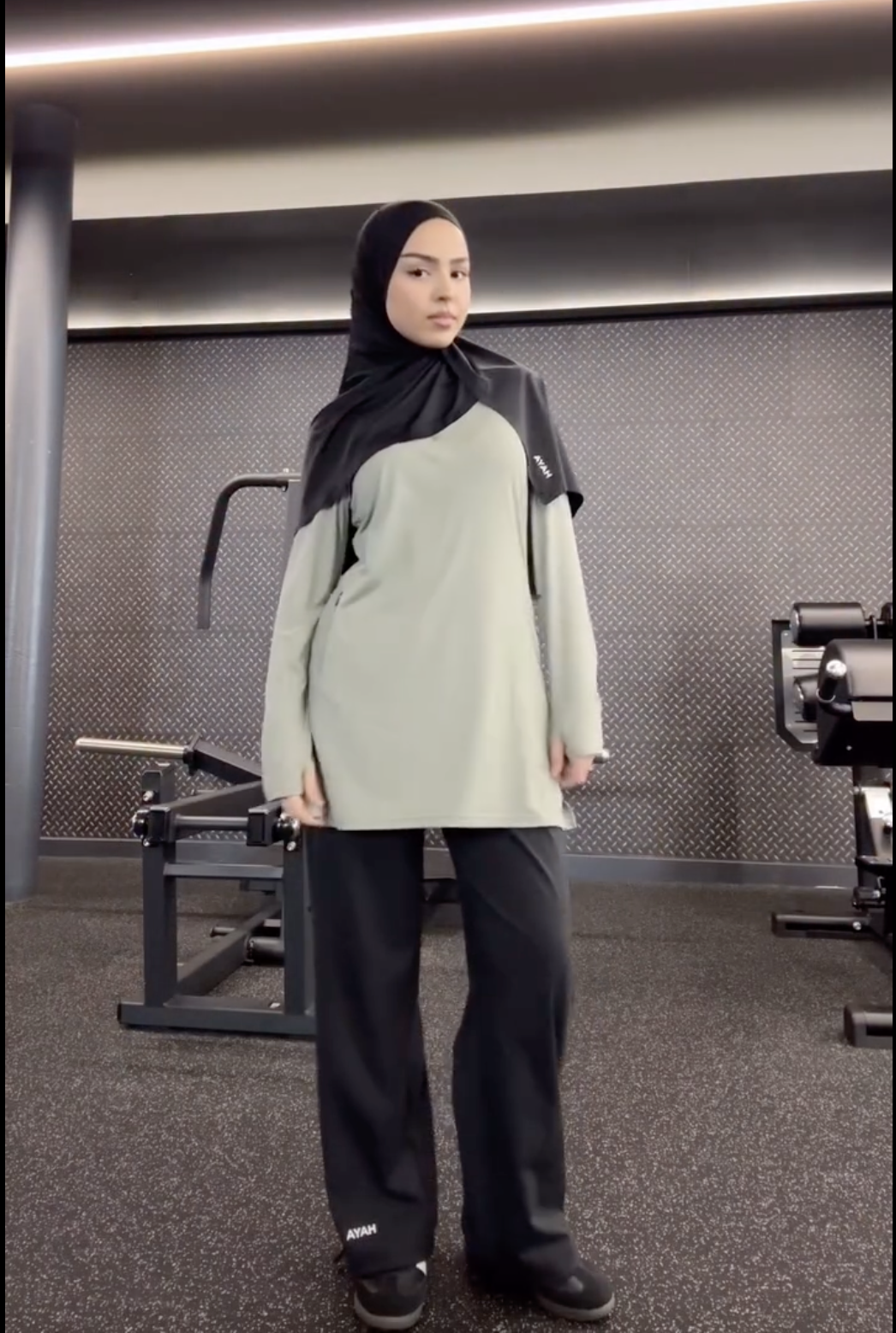 Person in gym attire standing in a fitness center.