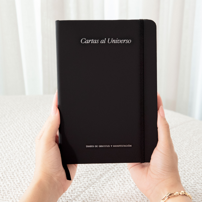 Person holding a black notebook with white text.