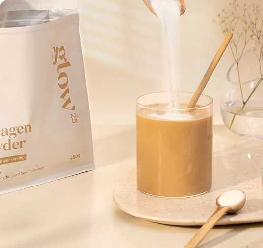 Collagen powder being poured into a glass of beige liquid.