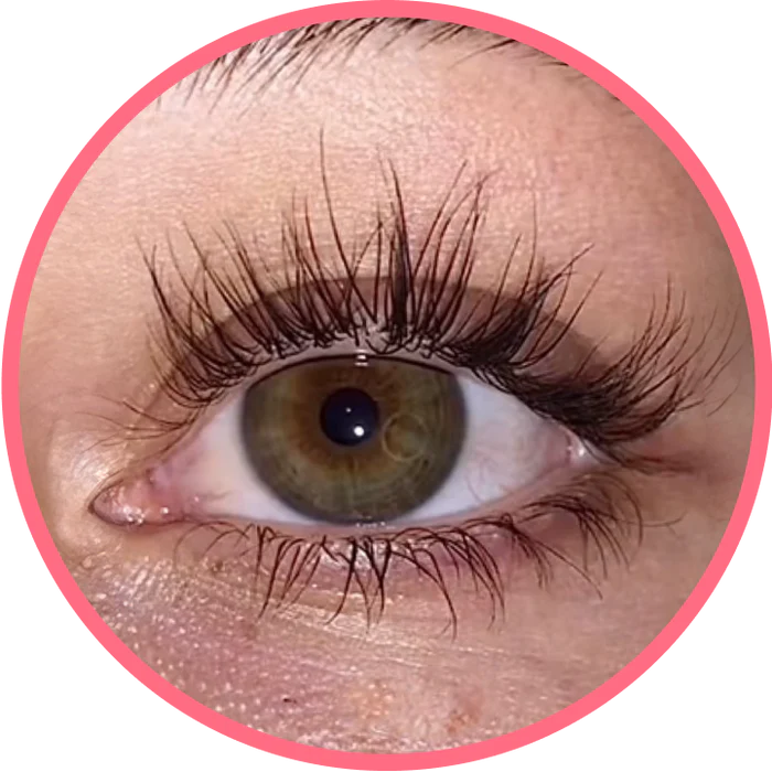 A close-up of a person's hazel eye with long black eyelashes, framed in a pink circle.