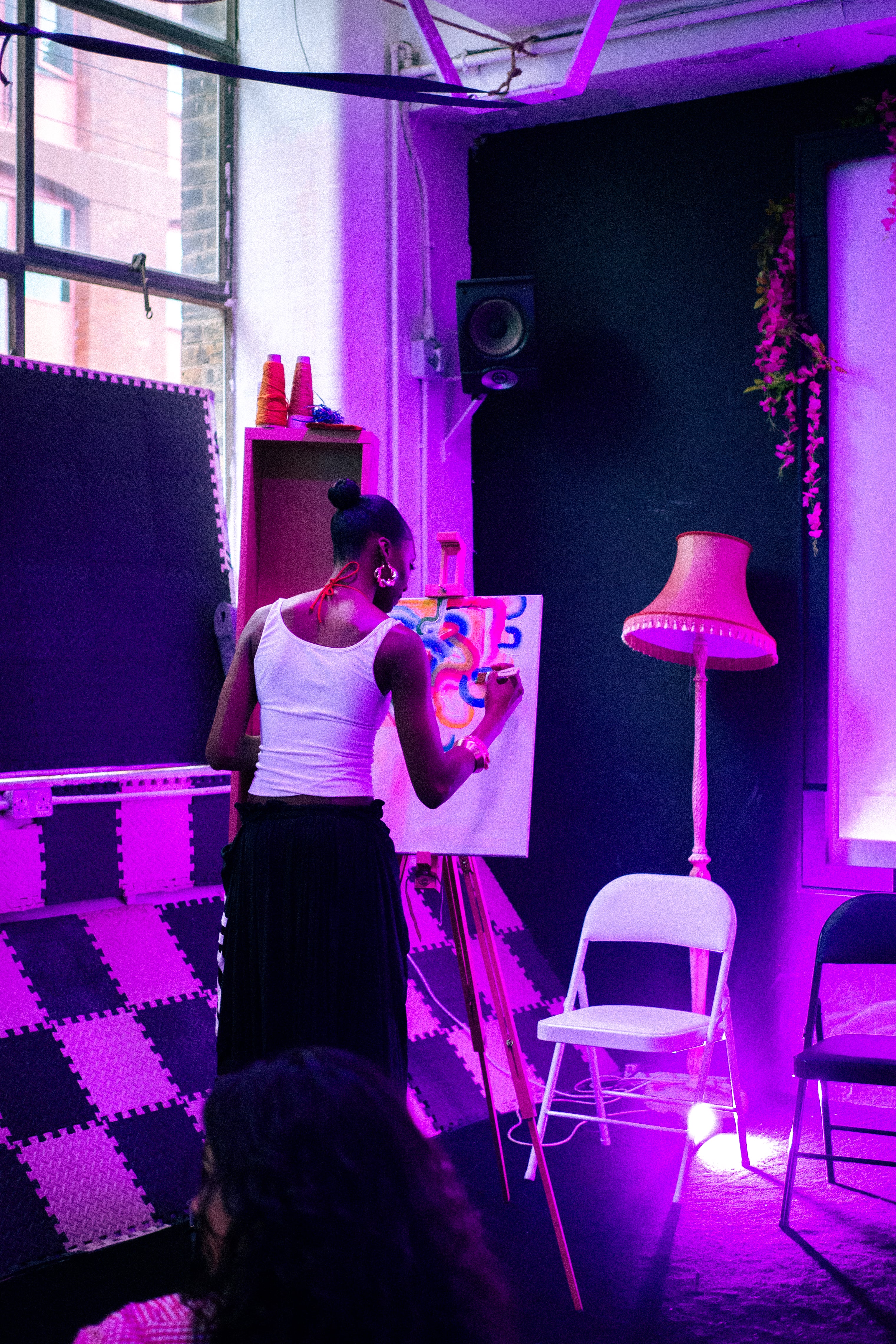 Person painting on a canvas in a room with purple lighting.