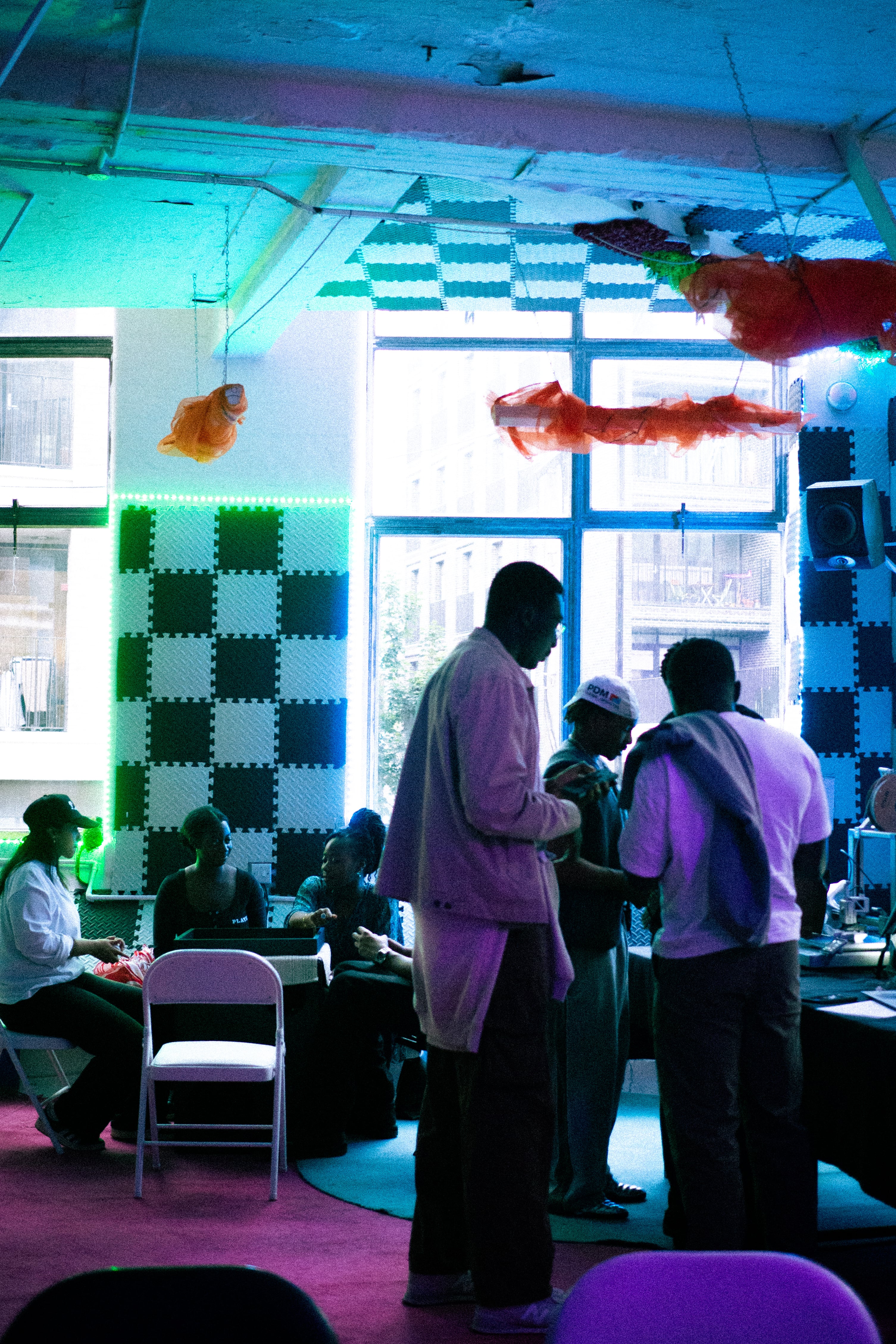 People socializing in a room with colorful lighting and checkered wall panels.