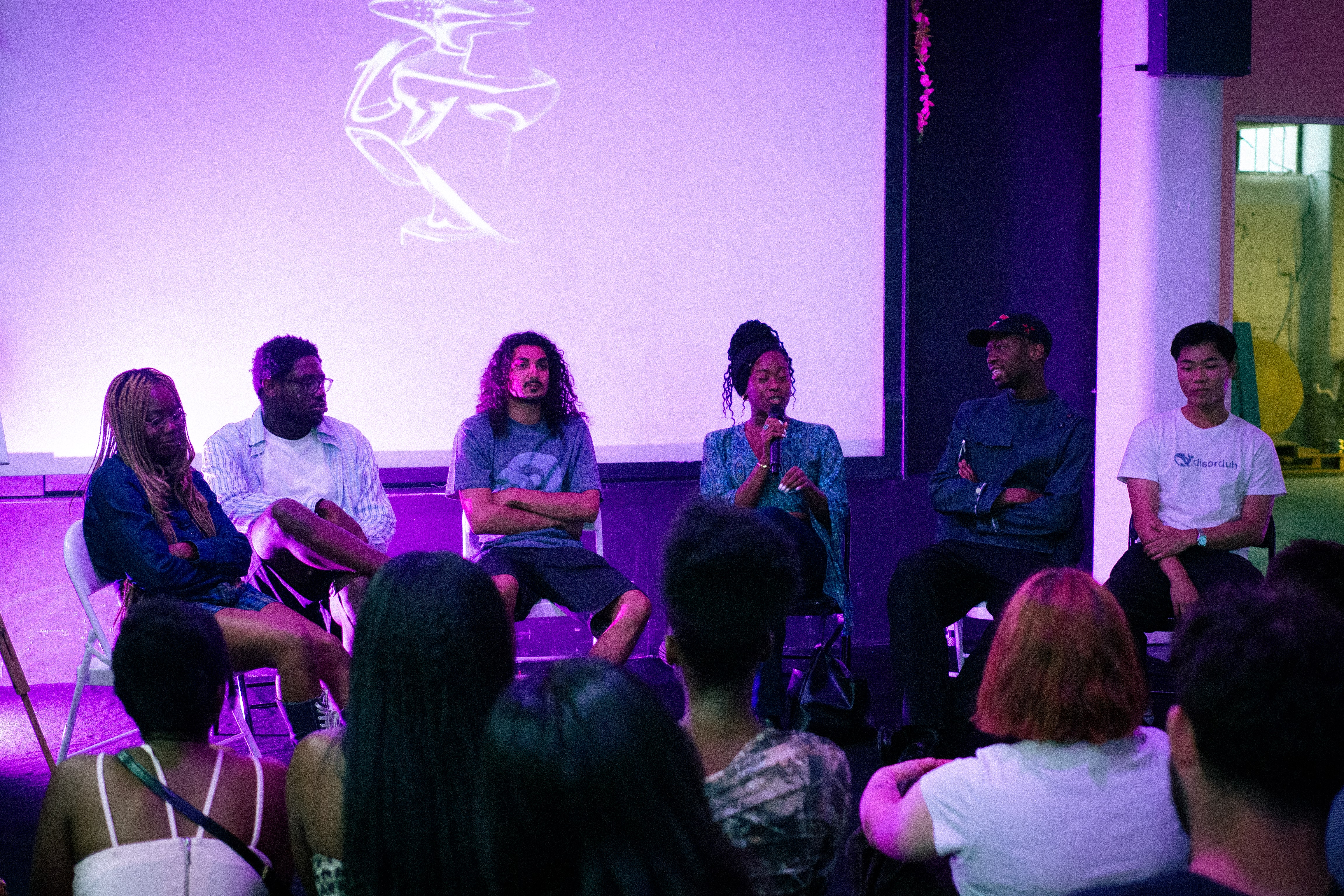 Panel discussion with six people seated, one speaking into a microphone.