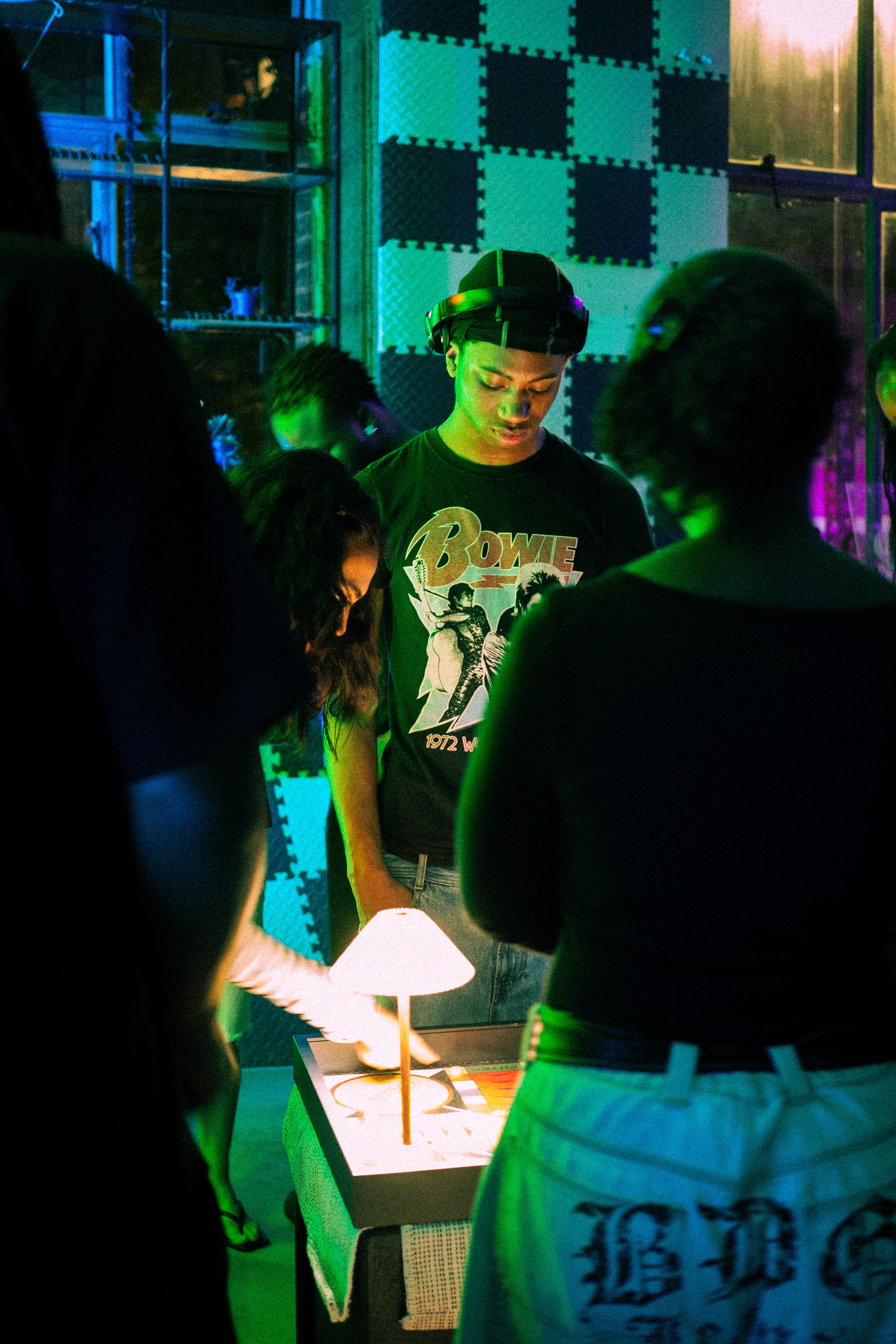 People gathered around a small lit table in a dimly lit room.