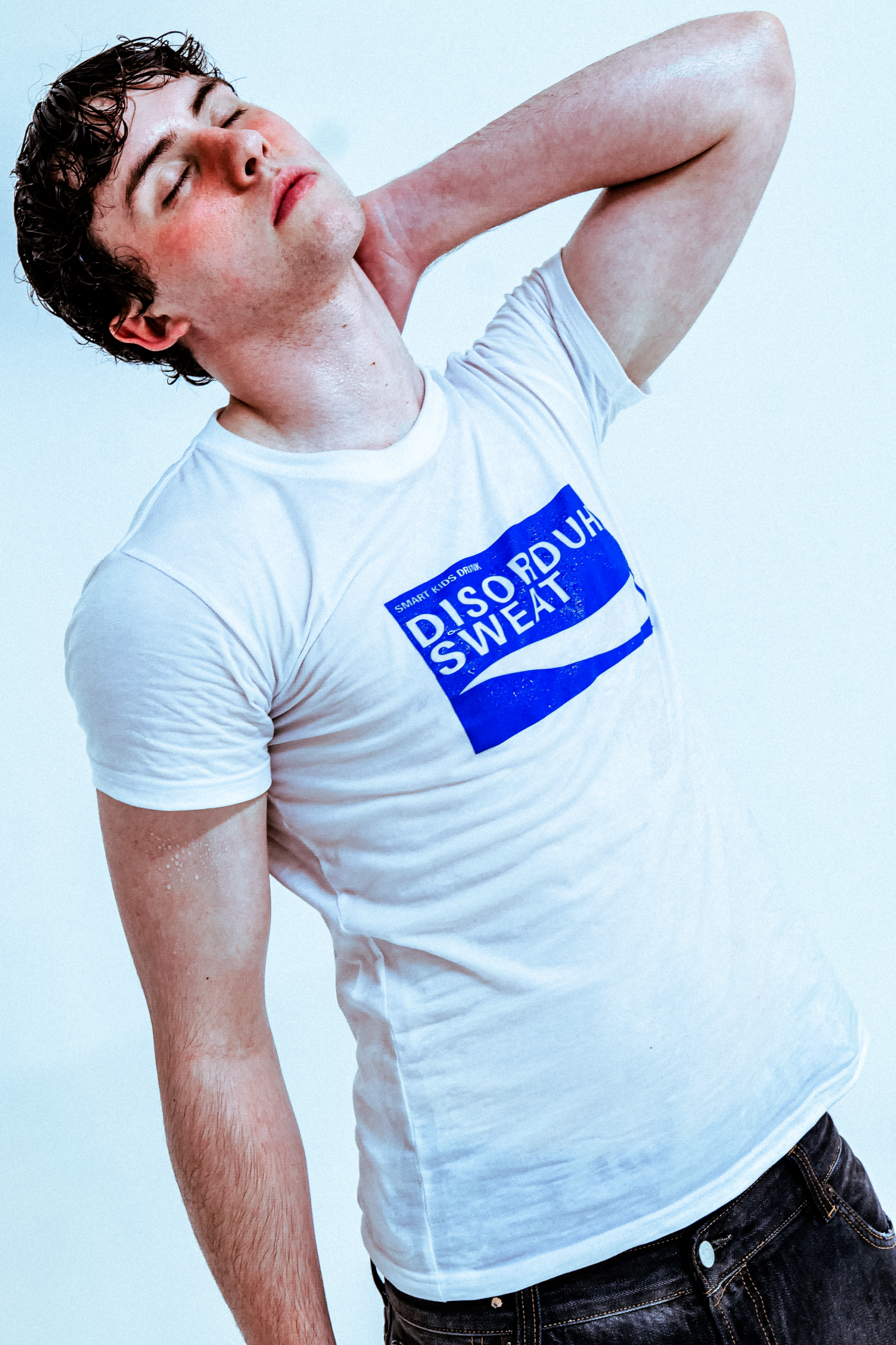 Person in a white t-shirt with blue text, posing with eyes closed.